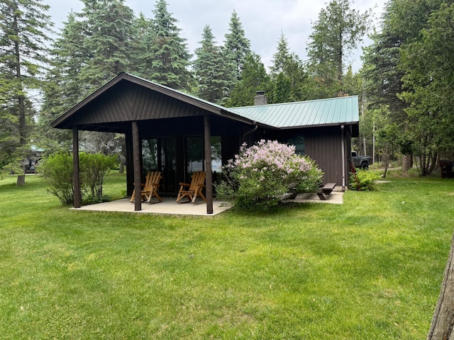 451 Gower Ln, Cheboygan, MI 49721 - back of house with a chimney, a lawn, a patio, and a metal roof