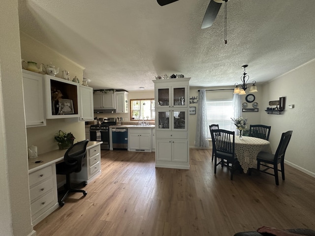 1632 Lakeview Dr, Alpena, MI 49707 - kitchen with stainless steel gas stove, dishwashing machine, light wood-style flooring, white cabinets, and a desk