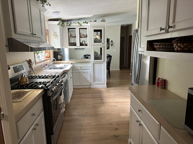 1632 Lakeview Dr, Alpena, MI 49707 - kitchen with gas range, light wood-style floors, ventilation hood, a textured ceiling, and glass insert cabinets