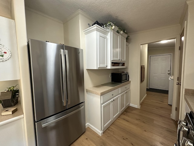 1632 Lakeview Dr, Alpena, MI 49707 - kitchen featuring freestanding refrigerator, crown molding, light countertops, light wood-style flooring, and white cabinets