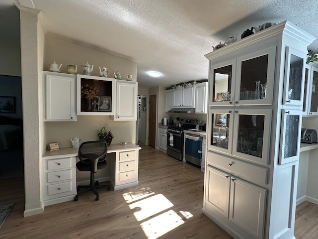 1632 Lakeview Dr, Alpena, MI 49707 - kitchen featuring under cabinet range hood, dishwashing machine, gas stove, light wood-style flooring, and white cabinets