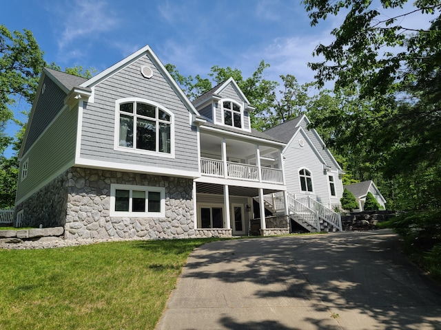 5825 Arawak Pass, Gaylord, MI 49735 - view of front of home with stone siding, stairs, a front yard, and a shingled roof