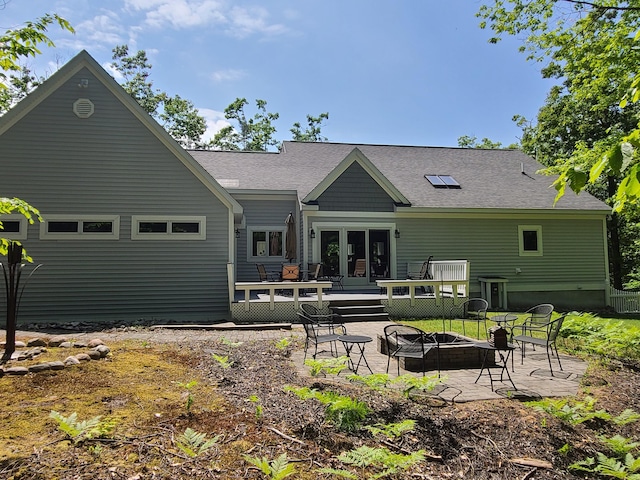 5825 Arawak Pass, Gaylord, MI 49735 - rear view of house featuring an outdoor fire pit, a deck, a patio area, and a shingled roof