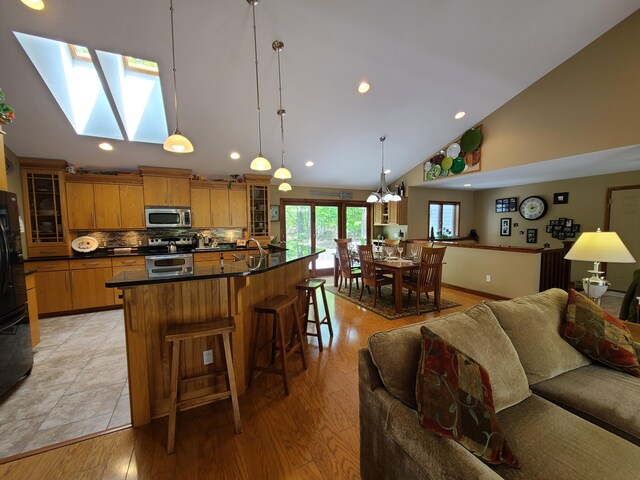5825 Arawak Pass, Gaylord, MI 49735 - kitchen featuring stainless steel appliances, dark countertops, glass insert cabinets, recessed lighting, and high vaulted ceiling
