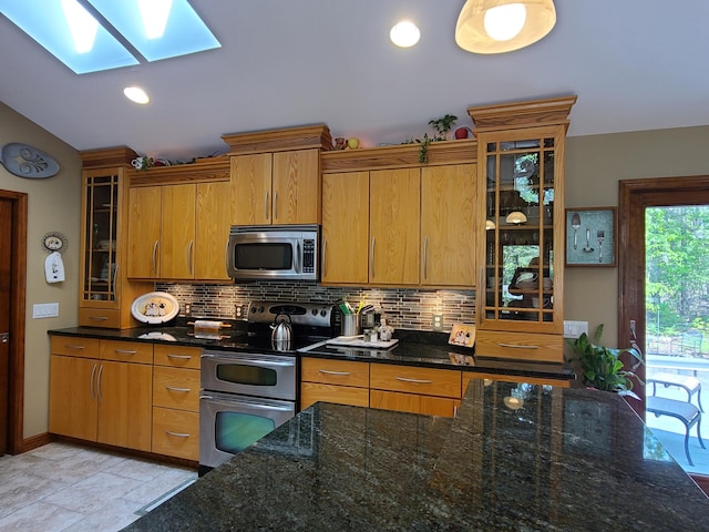 5825 Arawak Pass, Gaylord, MI 49735 - kitchen with appliances with stainless steel finishes, a skylight, backsplash, brown cabinetry, and vaulted ceiling