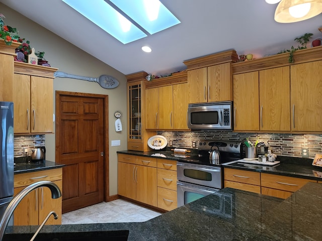 5825 Arawak Pass, Gaylord, MI 49735 - kitchen with stainless steel appliances, a skylight, vaulted ceiling, backsplash, and dark stone counters