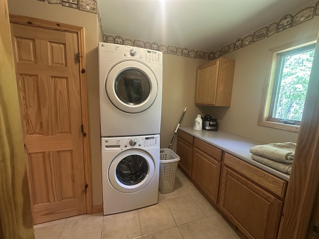 18440 Hardwood Trl, Hillman, MI 49746 - laundry room featuring stacked washer / dryer, cabinet space, and light tile patterned floors
