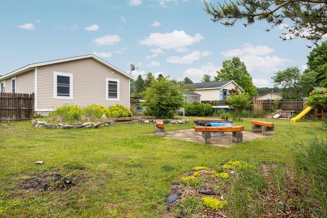 8934 Roberts Rd, Mancelona, MI 49659 - fenced backyard featuring a patio, an outdoor fire pit, and a playground