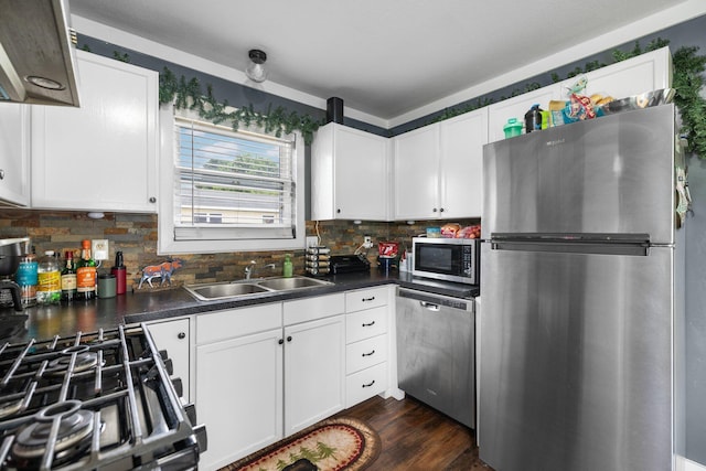 8934 Roberts Rd, Mancelona, MI 49659 - kitchen with appliances with stainless steel finishes, dark countertops, decorative backsplash, and white cabinetry