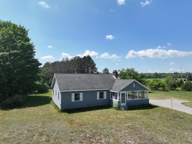 3090 S 37th Rd, Cadillac, MI 49601 - view of front of house with a sunroom, a chimney, a front lawn, and roof with shingles