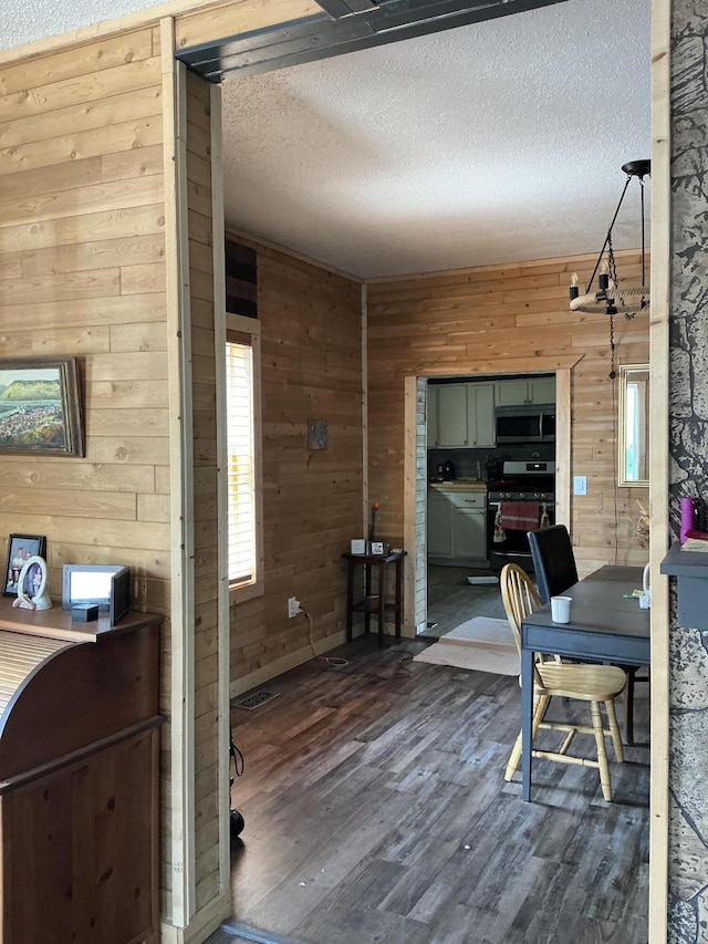 314 Sable St, Alpena, MI 49707 - dining room with wooden walls, a textured ceiling, and dark wood-style floors
