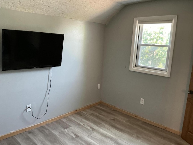 314 Sable St, Alpena, MI 49707 - unfurnished bedroom featuring lofted ceiling, a textured ceiling, and light wood-type flooring