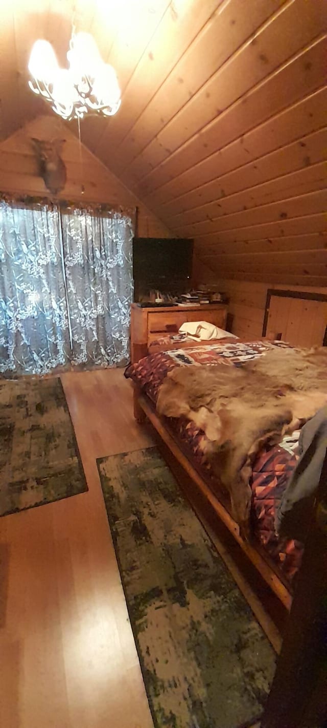 5597 Sunridge Dr, Elmira, MI 49730 - bedroom featuring lofted ceiling, wood finished floors, and a chandelier