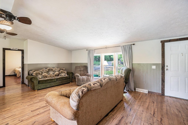 7539 E M-32, Johannesburg, MI 49751 - living room with a textured ceiling, wood-type flooring, a ceiling fan, and a wainscoted wall