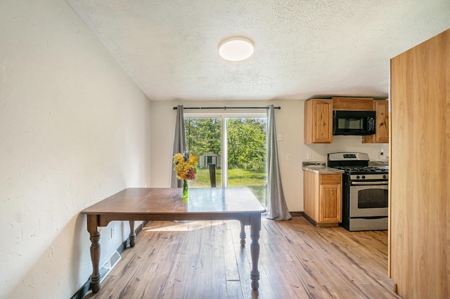 7539 E M-32, Johannesburg, MI 49751 - kitchen with stainless steel gas range oven, black microwave, a textured ceiling, light wood finished floors, and brown cabinetry