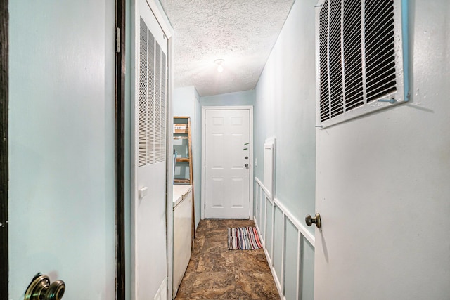 7539 E M-32, Johannesburg, MI 49751 - hallway featuring a heating unit, dark stone finish floors, a textured ceiling, and washer / dryer