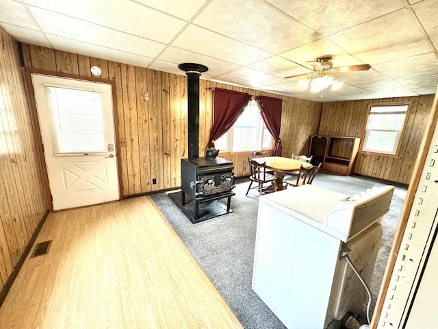 2833 S Horseshoe Trl, Grayling, MI 49738 - living room with a wood stove, healthy amount of natural light, ceiling fan, wood walls, and wood finished floors