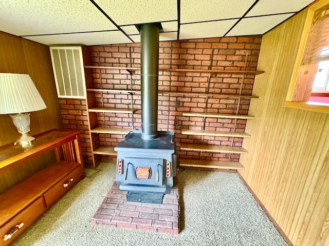2833 S Horseshoe Trl, Grayling, MI 49738 - unfurnished living room with carpet, wooden walls, a drop ceiling, and a wood stove