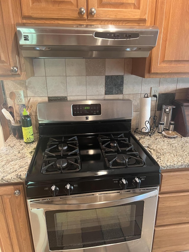268 Yorke Trl, Grayling, MI 49738 - kitchen view of stainless steel gas range, extractor fan, tasteful backsplash, and light stone countertops