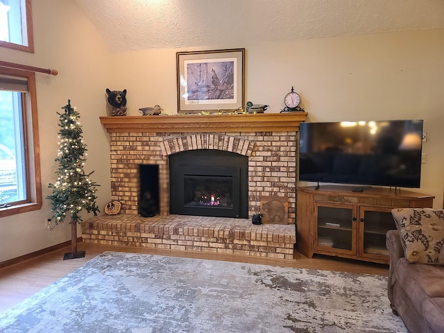 1514 Opal Lake Rd, Gaylord, MI 49735 - living area featuring a textured ceiling, wood finished floors, vaulted ceiling, and a fireplace