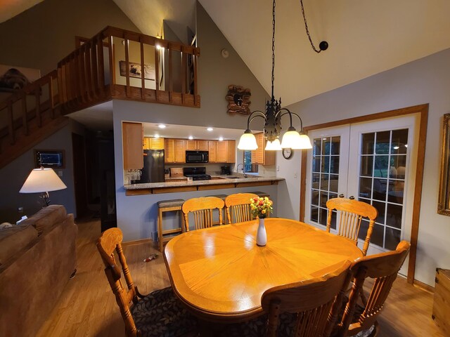 1514 Opal Lake Rd, Gaylord, MI 49735 - dining area featuring high vaulted ceiling, wood finished floors, french doors, a chandelier, and stairway