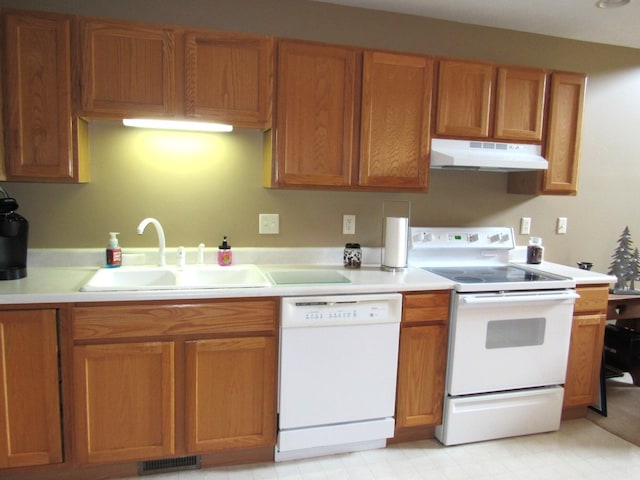 201 White Deer Trl, Prudenville, MI 48651 - kitchen with white appliances, under cabinet range hood, light countertops, and brown cabinetry