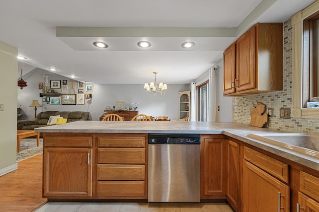 1655 Arrowhead Trl, West Branch, MI 48661 - kitchen featuring stainless steel dishwasher, a peninsula, a chandelier, light countertops, and decorative backsplash