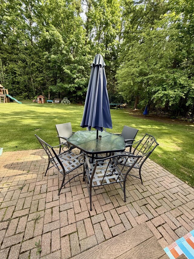 2176 Deepwoods Dr, Gaylord, MI 49735 - view of patio featuring a playground, outdoor dining space, and view of scattered trees