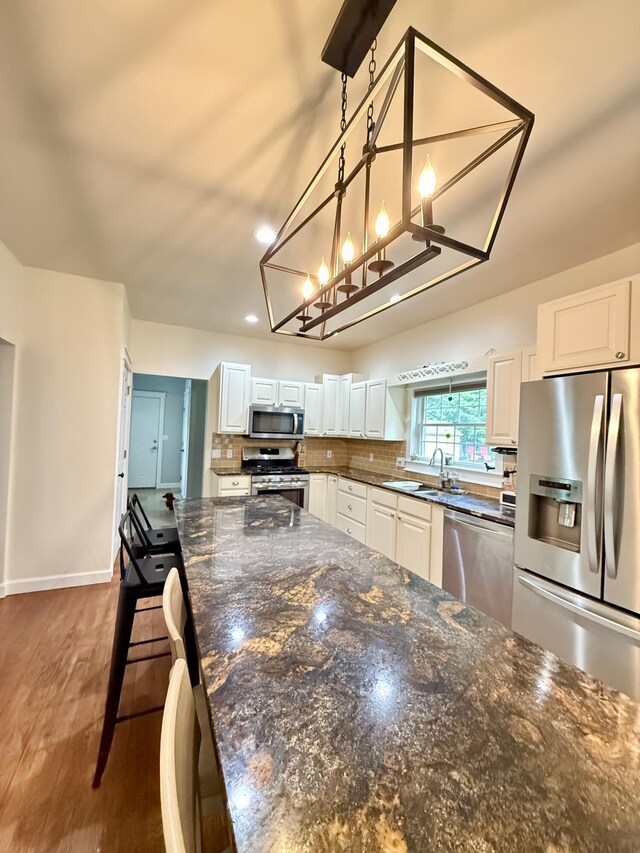 2176 Deepwoods Dr, Gaylord, MI 49735 - kitchen with appliances with stainless steel finishes, white cabinetry, decorative backsplash, wood finished floors, and recessed lighting
