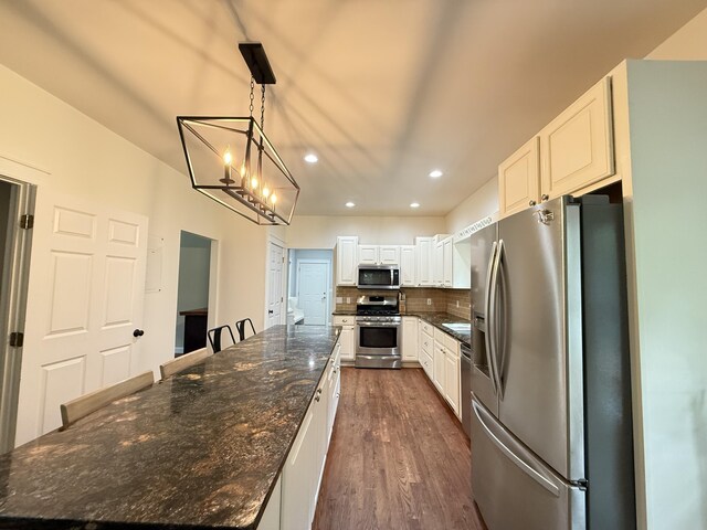 2176 Deepwoods Dr, Gaylord, MI 49735 - kitchen with appliances with stainless steel finishes, a large island, a chandelier, dark wood-style floors, and decorative backsplash