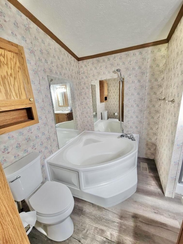 2651 Chipmunk Trl, Grayling, MI 49738 - bathroom with wood finished floors, ornamental molding, a textured ceiling, wallpapered walls, and a bath