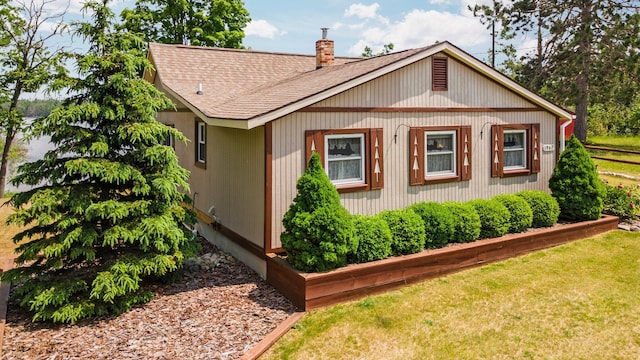 1960 Highbank Trl, Lewiston, MI 49756 - view of side of home with roof with shingles, a chimney, and a yard