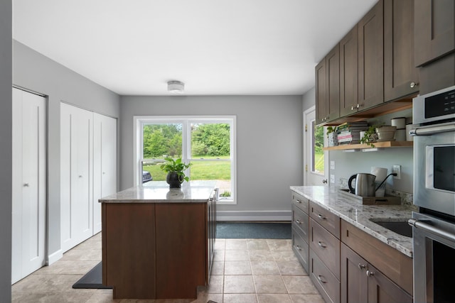 9660 Richardson Rd, Cheboygan, MI 49721 - kitchen with open shelves, a center island, light stone counters, double oven, and dark brown cabinetry