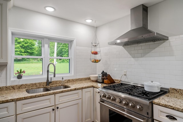 9660 Richardson Rd, Cheboygan, MI 49721 - kitchen with wall chimney range hood, high end range, tasteful backsplash, light stone counters, and white cabinetry