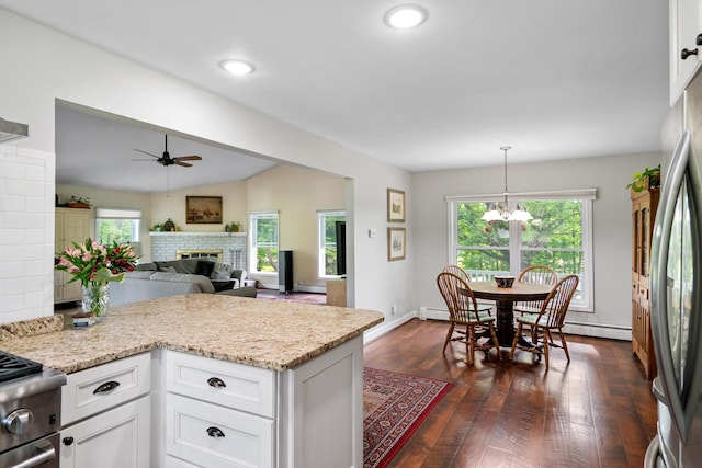 9660 Richardson Rd, Cheboygan, MI 49721 - kitchen with a ceiling fan, a brick fireplace, white cabinets, a chandelier, and dark wood finished floors