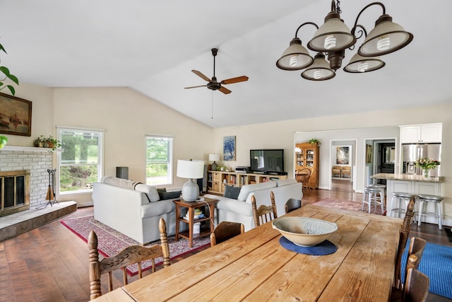 9660 Richardson Rd, Cheboygan, MI 49721 - dining space with dark wood-type flooring, lofted ceiling, a ceiling fan, a chandelier, and a fireplace