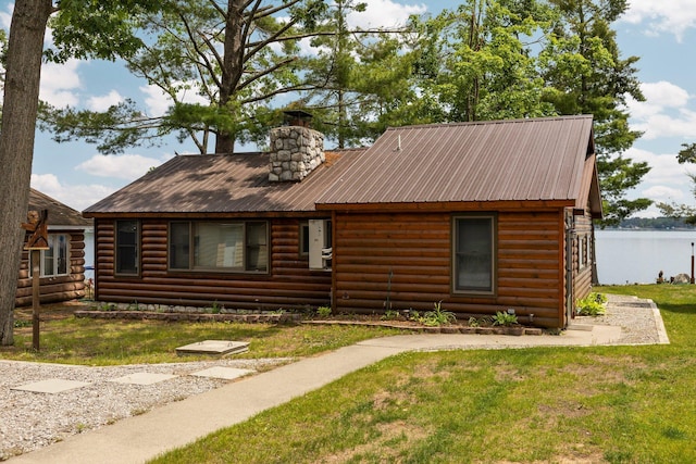 2061 Dreamers Ln, Lewiston, MI 49756 - view of front of house with faux log siding, a front lawn, a chimney, and a metal roof