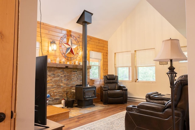 4696 Glacial Field Dr, Elmira, MI 49730 - living area featuring a wood stove, baseboard heating, wood finished floors, and vaulted ceiling