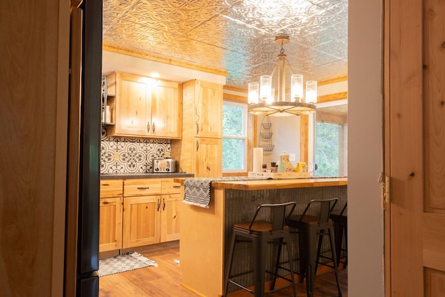 4696 Glacial Field Dr, Elmira, MI 49730 - indoor dry bar featuring a chandelier, an ornate ceiling, light wood-type flooring, refrigerator, and decorative backsplash