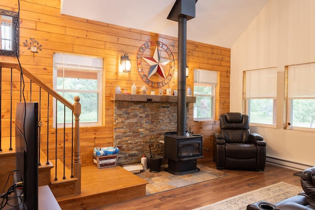 4696 Glacial Field Dr, Elmira, MI 49730 - living area featuring a wood stove, baseboard heating, wooden walls, wood finished floors, and stairs