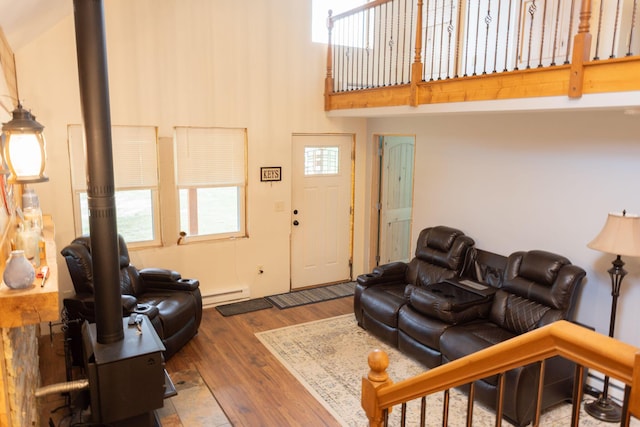 4696 Glacial Field Dr, Elmira, MI 49730 - living room with a baseboard radiator, a towering ceiling, wood finished floors, and a wood stove