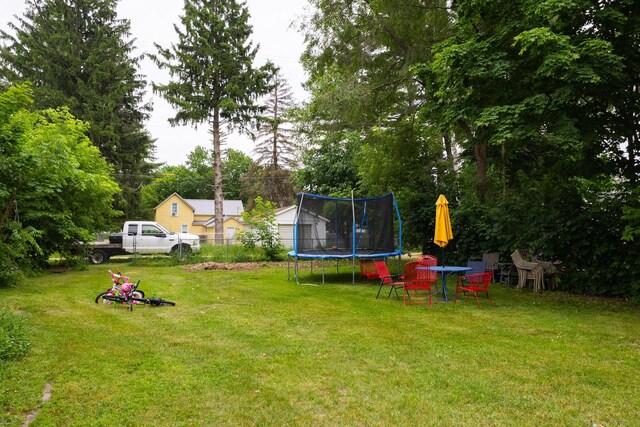 210 N Maple St, Mancelona, MI 49659 - view of yard featuring a trampoline, a shed, and view of wooded area
