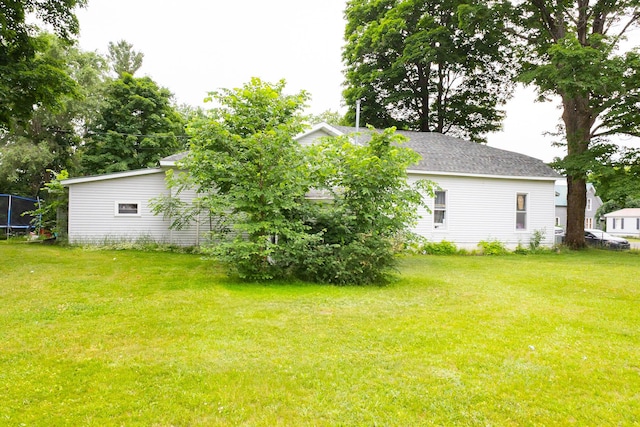 210 N Maple St, Mancelona, MI 49659 - view of grassy yard featuring a trampoline
