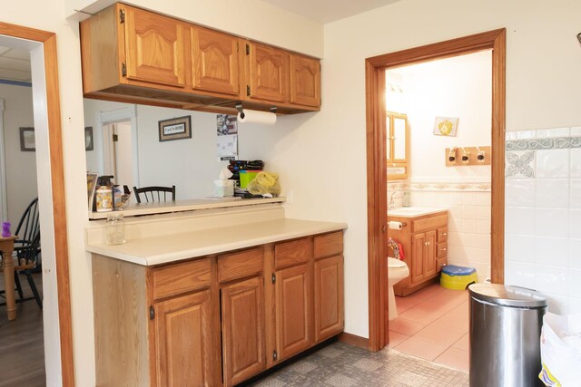 210 N Maple St, Mancelona, MI 49659 - kitchen featuring light countertops, tile walls, brown cabinetry, and dark tile patterned floors