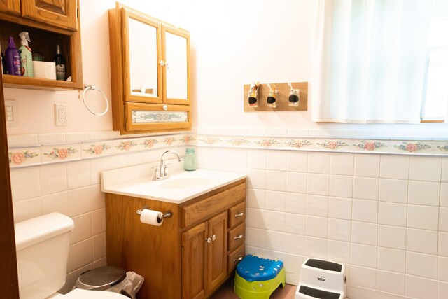 210 N Maple St, Mancelona, MI 49659 - bathroom with vanity, tile walls, and a wainscoted wall