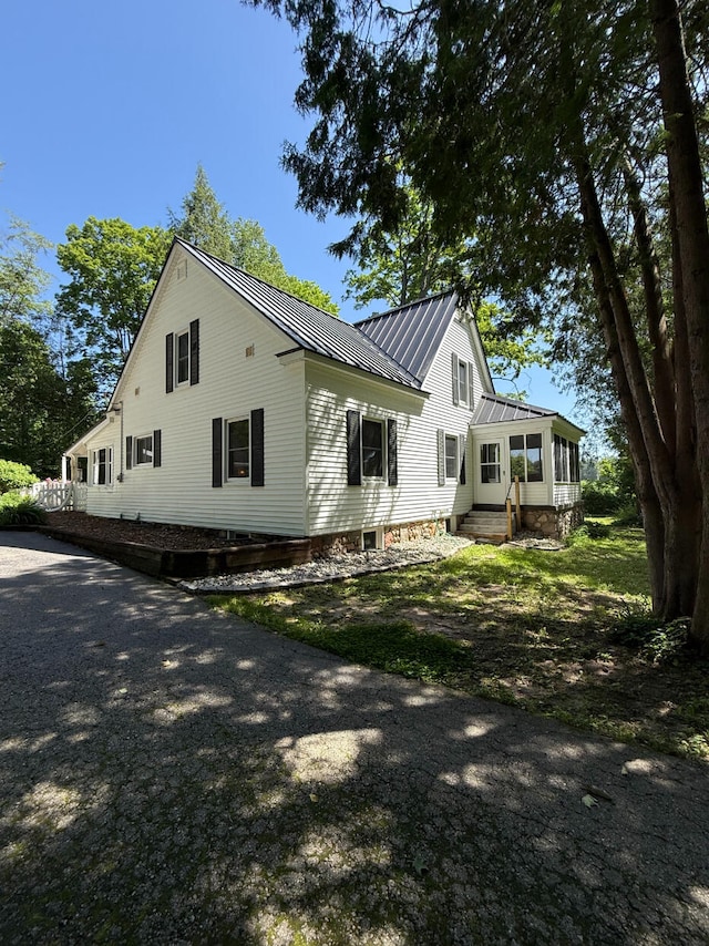 3628 Rau Rd, West Branch, MI 48661 - view of property exterior featuring a sunroom, a metal roof, and entry steps