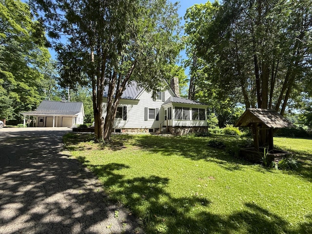3628 Rau Rd, West Branch, MI 48661 - view of front facade with a sunroom, a chimney, a standing seam roof, an outbuilding, and driveway
