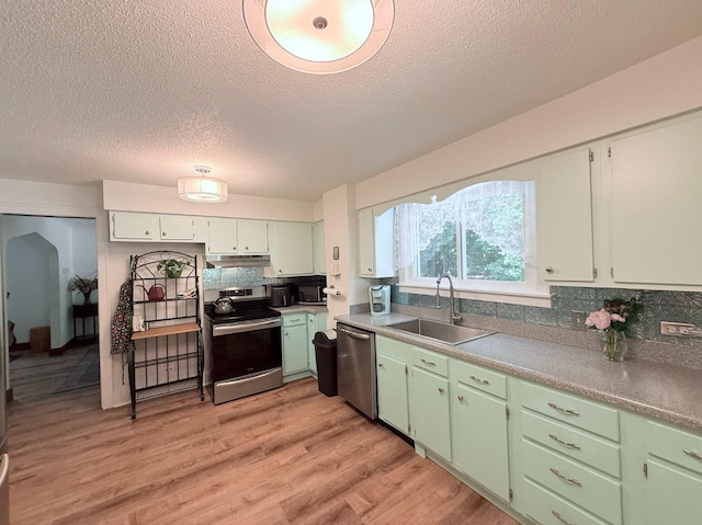 3628 Rau Rd, West Branch, MI 48661 - kitchen featuring appliances with stainless steel finishes, a textured ceiling, tasteful backsplash, under cabinet range hood, and light wood-style flooring