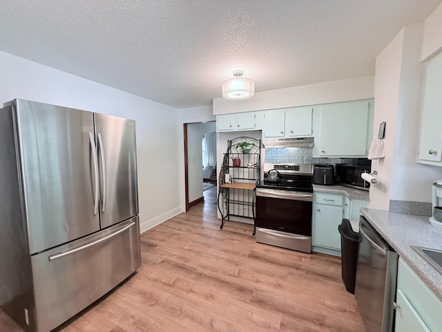 3628 Rau Rd, West Branch, MI 48661 - kitchen with appliances with stainless steel finishes, under cabinet range hood, light wood finished floors, a textured ceiling, and light countertops