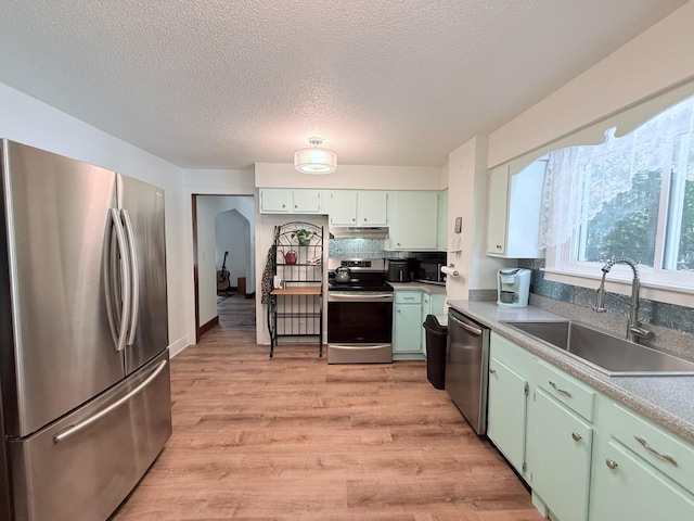 3628 Rau Rd, West Branch, MI 48661 - kitchen featuring stainless steel appliances, green cabinetry, light wood finished floors, under cabinet range hood, and a textured ceiling